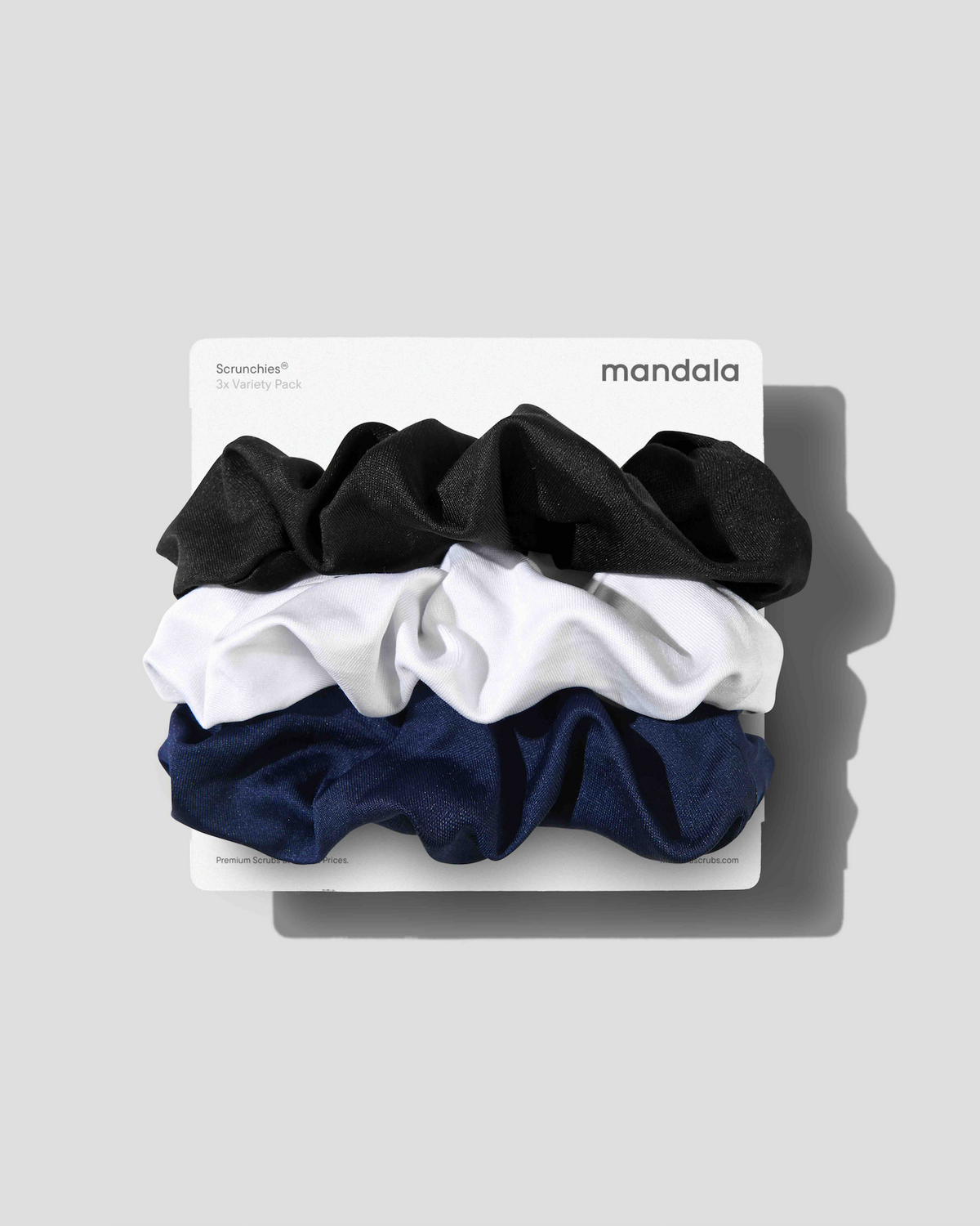 A three-pack of Mandala Bounceies hair scrunchies in black, white, and navy blue, stacked on a white cardboard backing against a light gray background.